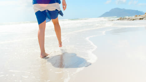 sección baja de la mujer caminando en la playa en un día soleado 4k