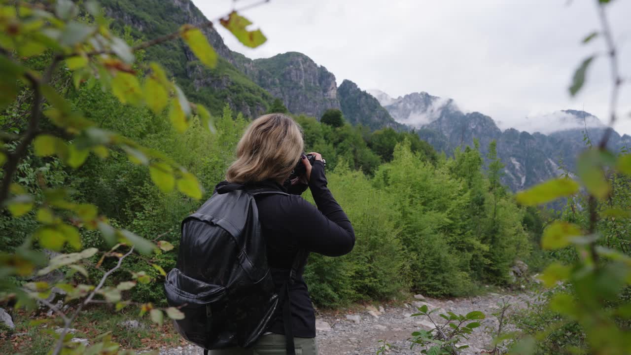 Female photographer clicking pictures of Albanian alps while hiking, Theth