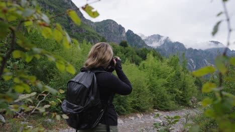 female photographer clicking pictures of albanian alps while hiking, theth