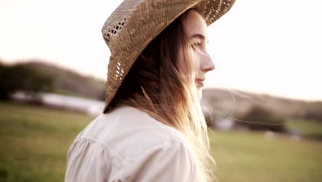 attractive young woman with straw hat walking in a farm