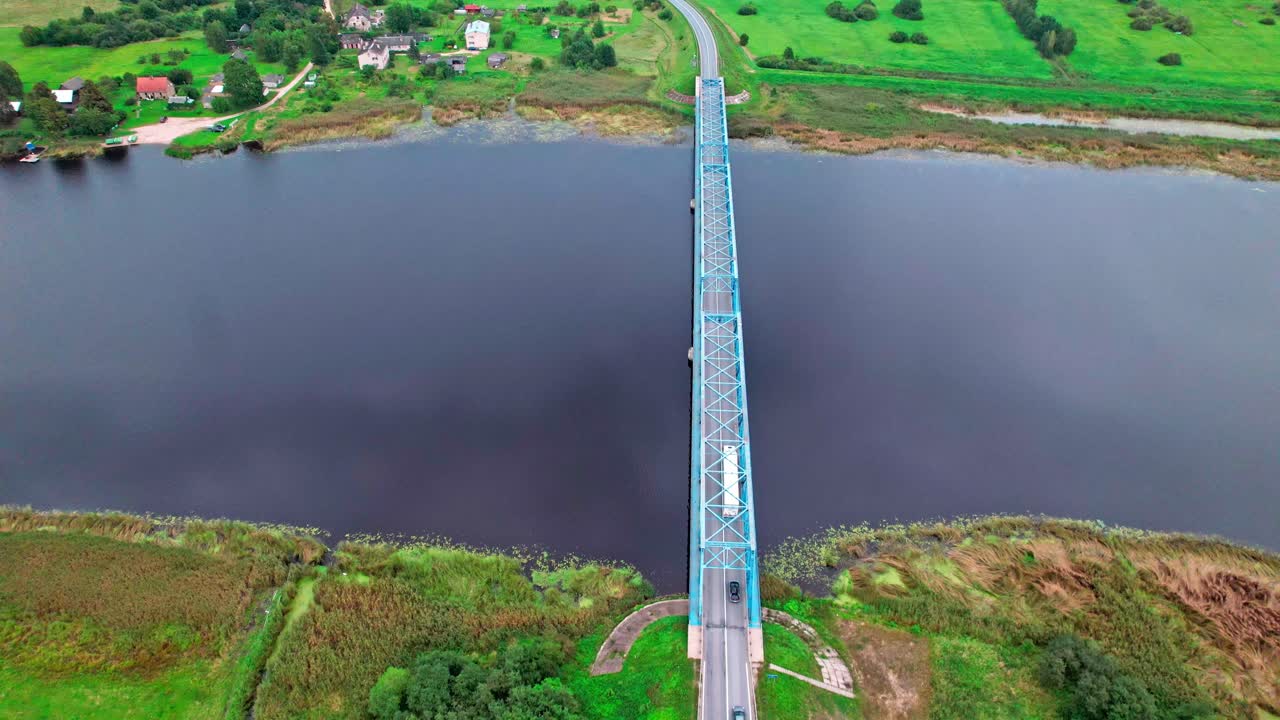 Aerial view of a bridge over a river in Latvia amidst lush greenery