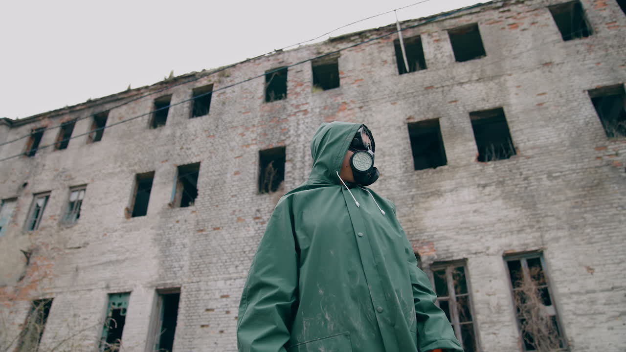 Environmentalist in protective suit and gas mask. Man in gas mask near abandoned destroyed building