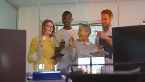 Front-view-of-young-mixed-race-business-team-discussing-over-glass-wall-in-modern-office-4k