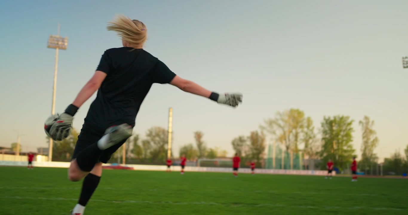 Torhüterin tritt einen Fußball und beobachtet das Spiel auf dem Spielfeld