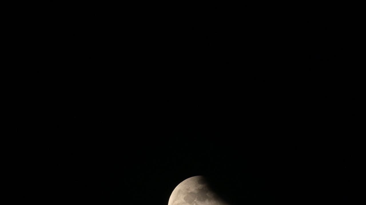 Lua subindo da parte inferior do quadro, parcialmente coberta por alguma sombra no lado superior direito, Eclipse Lunar na Tailândia em 8 de novembro de 2022.