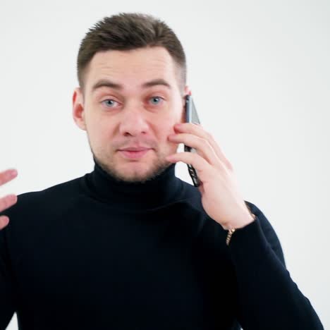 Professional creative man talking on the smartphone. Handsome man in black sweater using mobile phone isolated on white studio background.