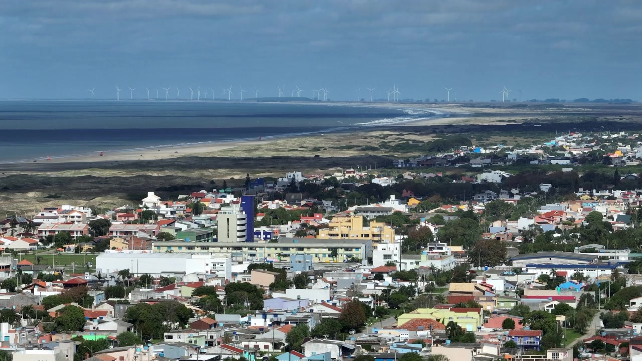 Staattinen telekuva ilmasta Balneario Cassinon kaupunkimaisemasta, jossa näkyy maailman pisin ranta, Atlantin valtameri ja tuulipuisto horisontissa, Rio Grande do Sul, Brasilia