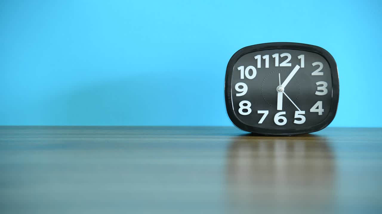 Time lapse of black alarm clock on wooden table