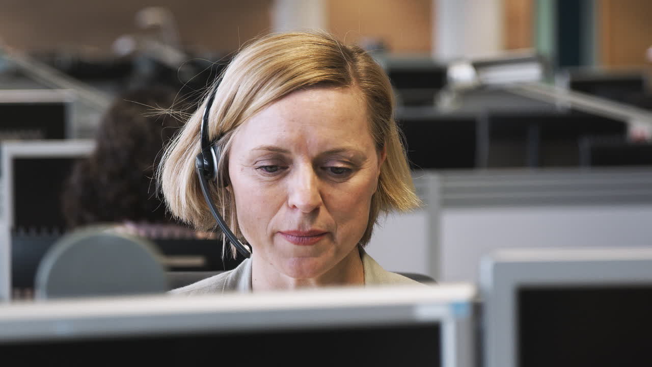 Moden forretningskvinne iført telefonhodesett snakker med innringer i kundeserviceavdeling