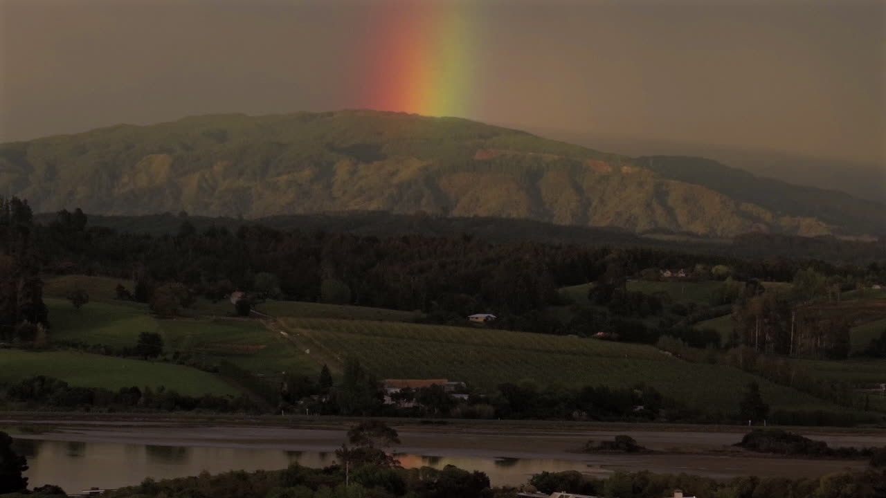 tomada de un avión no tripulado de un gran arco iris en la distancia sobre el valle de motueka en nueva zelanda