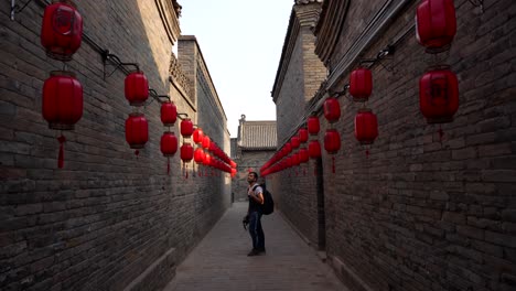 european man looking at the red lanterns of the bricked walls in pingyao, china