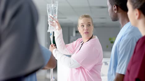médica caucásica entrenando a diversos médicos en prácticas, aplicando goteo, cámara lenta