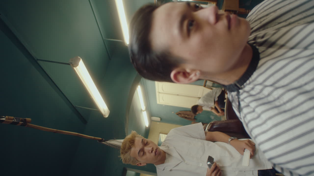 Asian Barber Serving Client Using Hair Clippers and Comb