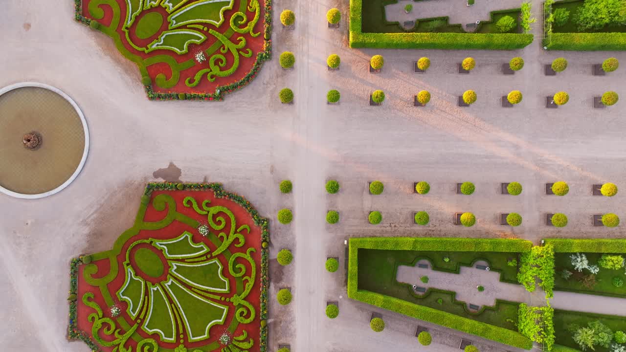Top down view reveals French garden symmetry and gravel paths in golden light