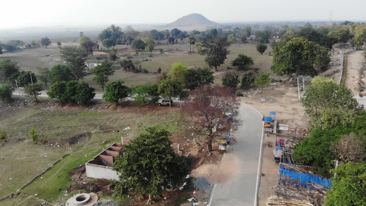 Aerial shot of a village in Jharkhand with asphalt road and green vegetations and mountain in India