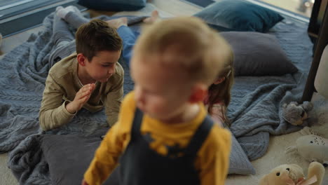 kids gaming smartphones. siblings lying with cell phones next kid on carpet.