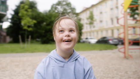 Little-girl-with-down-syndrome-playing-in-the-park-on-a-windy-day.-She-is-spinning-on-a-carousel