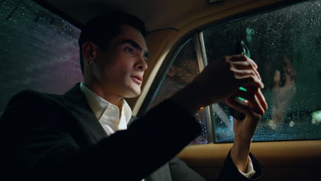 focused man using smartphone in dark car closeup. businessman tapping mobile