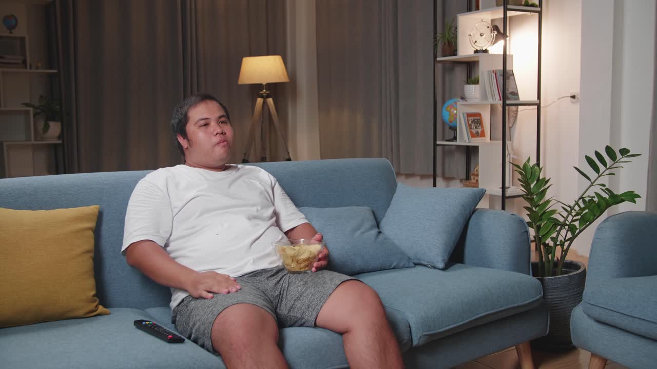 Man Eating Chips While Watching TV at Home