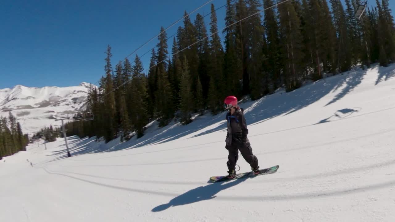 snowboarder montando goofy en la estación de esquí de colorado en un día de pájaro azul