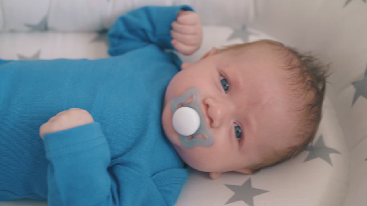 маленький ребенок сосет соски в уютном коконе в качающейся кроватке