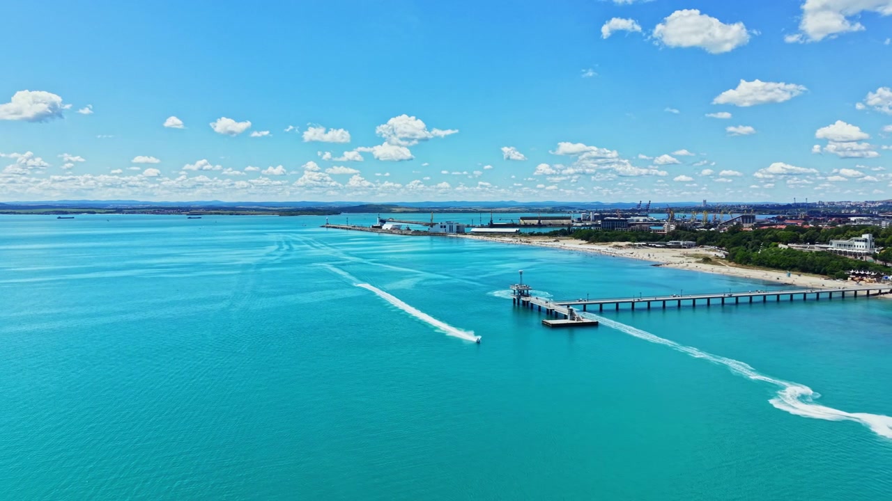 晴れた午後の都市近郊のビーチ。海と空が海岸線で溶け合い、遠くには船が浮かんでいる。