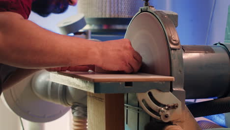 manufacturer shaping wooden bowl on disc sander in assembling shop