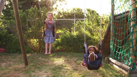 dos niñas jugando al aire libre en casa en columpios de jardín
