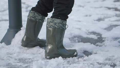 person walking in green boots through snow