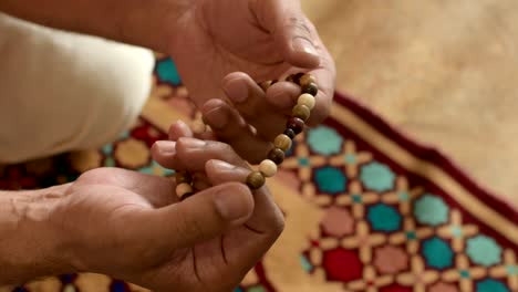 man's hand with wooden prayer beads, goes through prayer beads, blurred background. muslim prayer.