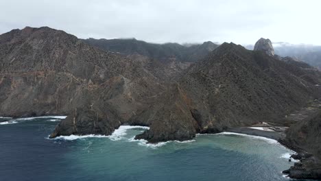 Aerial-drone-view-of-stunning-rugged-coastal-cliff-rock-formation-by-the-ocean-in-the-volcanic-island-of-La-Gomera,-Spain