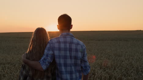 Pareja-Feliz-Admirando-La-Puesta-De-Sol-Sobre-Un-Campo-De-Trigo.-Vídeo-4k