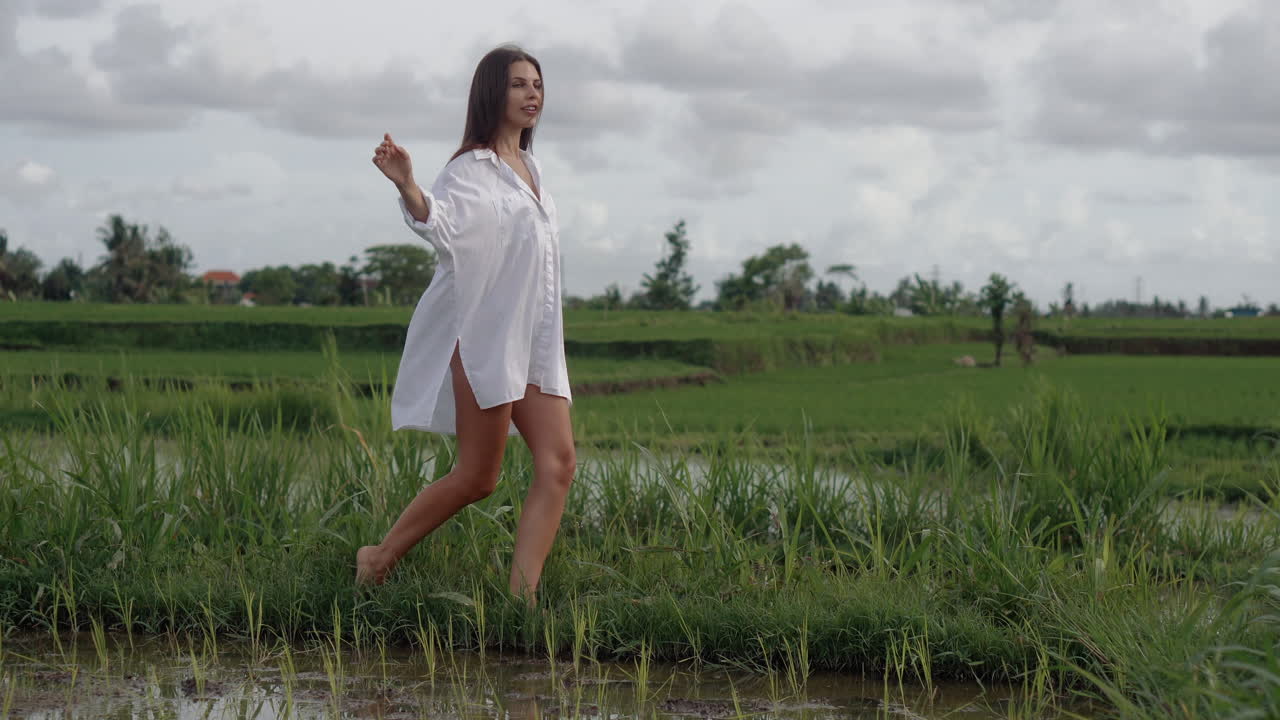 Woman Walking Through a Rice Paddy Field in Bali