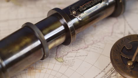 an antique brass telescope with sundial and compass on a vintage map of the world for plotting adventure