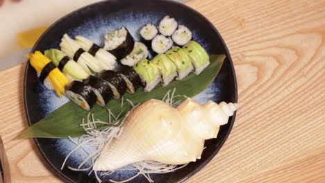 Teller-Mit-Sushi-Rollen-Und-Nigiri-Sushi,-Dekoriert-Mit-Muscheln-In-Einem-Japanischen-Restaurant