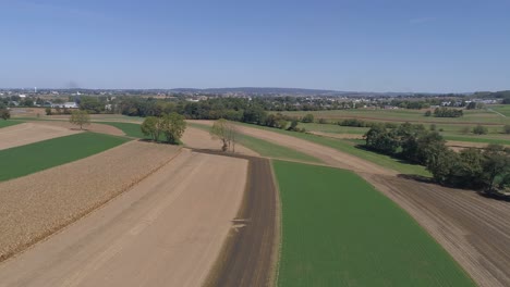 Luftaufnahme-Der-Amischen-Landschaft-Des-Landwirtschaftlichen-Arbeitsfeldes-An-Einer-Eisenbahnstrecke,-Während-Sich-Eine-Dampfmaschine-Nähert,-Wie-Sie-Von-Einer-Drohne-Gesehen-Wird