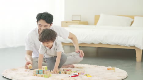 happy family father and child son laughing while stack blocks and play games toys together at home with a joyful atmosphere, enjoying leisure time in living room