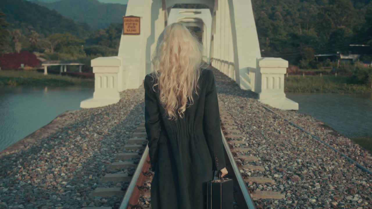 Woman Walking Across a Bridge on Train Tracks