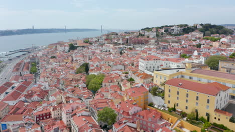 Flying-over-rooftops-of-colorful-houses-in-dense-urban-city-center-of-Lisbon,-Portugal.-Aerial-wide-panoramic-view-of-residential-houses-on-the-hill