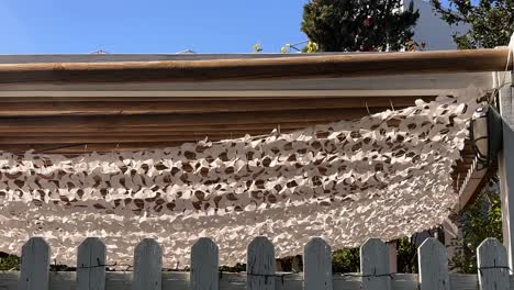 white decorative shade net over a wooden pergola with a fence in crete greece