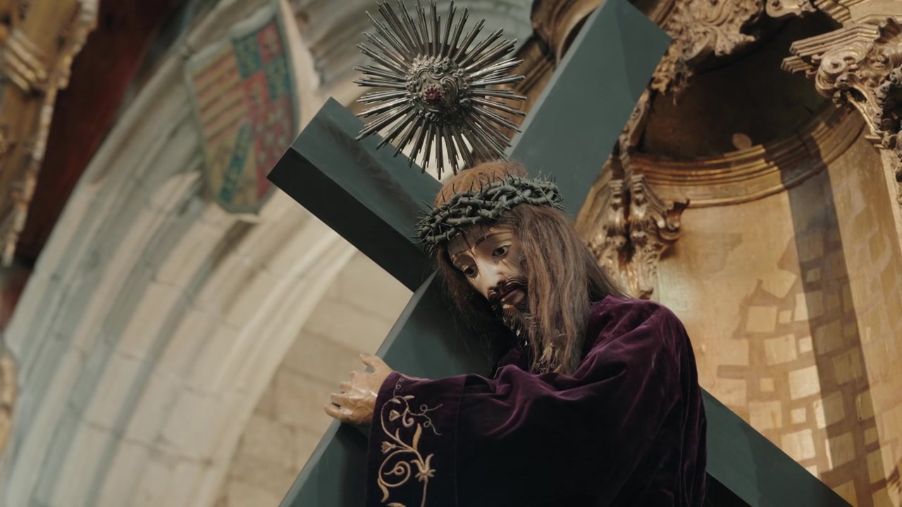 Statua devozionale di Gesù che porta la croce con la corona di spine in una chiesa barocca.
