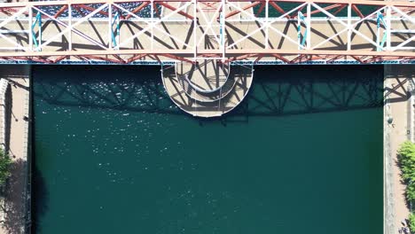 aerial drone flight over the bridge at salford quays the lowry centre showing a birdseye view of the green waters below