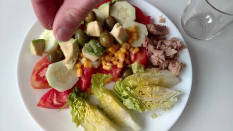 fresh mixed salad with cucumber, tomato, corn, tuna, and avocado, seasoned with salt