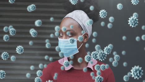 Animation-of-covid-19-cells-over-african-american-woman-wearing-face-mask