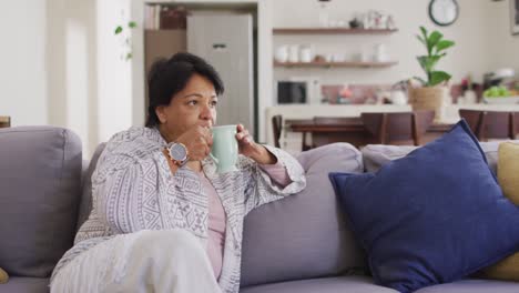 Asian-senior-woman-drinking-coffee-sitting-on-the-couch-at-home