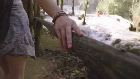Hand Touching Bamboo Fence With Waterfall At The Background, Slow Motion