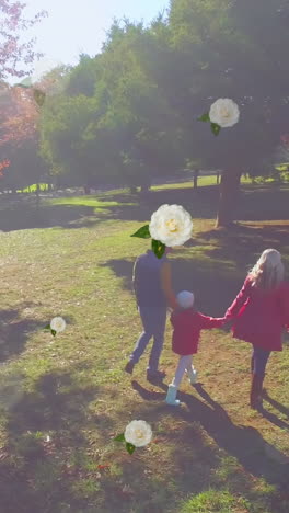 animation of flower icons over happy caucasian family in park