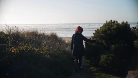 4k footage in slow motion of woman walking alone towards the beach while sunset through sand dunes