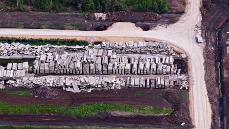 concrete debris and old construction materials stacked near unpaved road at industrial site