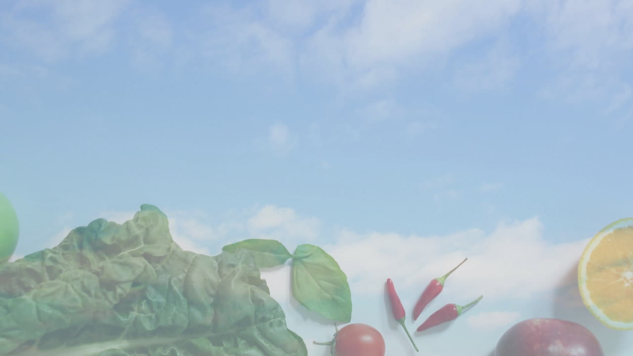 Fresh vegetables and fruits under blue sky with clouds in background